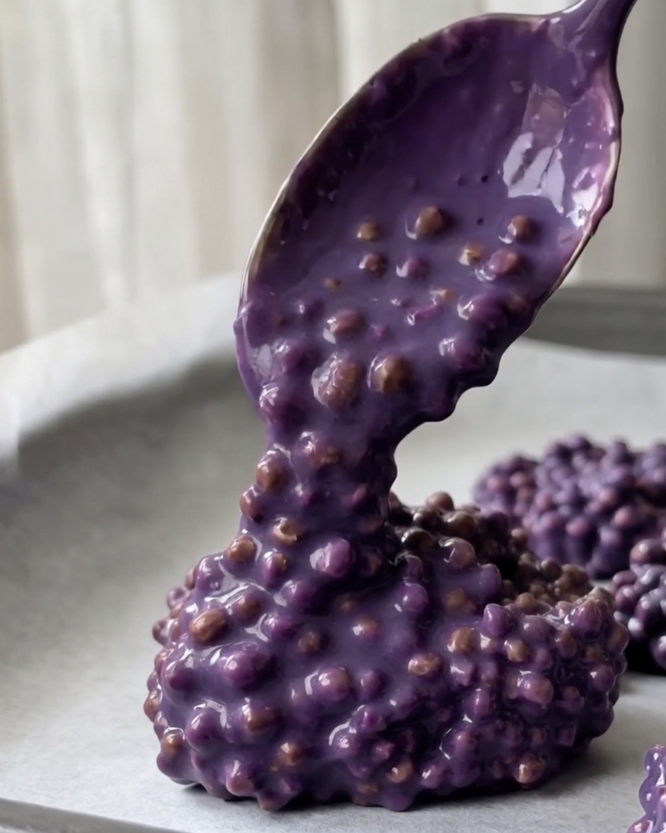 Spooning ube quinoa mixture into discs on parchment for Ube Nolia pistachio quinoa bites