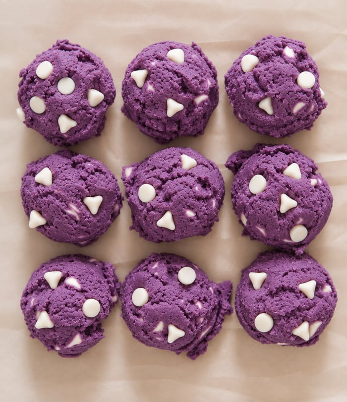 Ube cookie dough balls with white chocolate chunks on baking paper, purple yam | Ube Nolia
