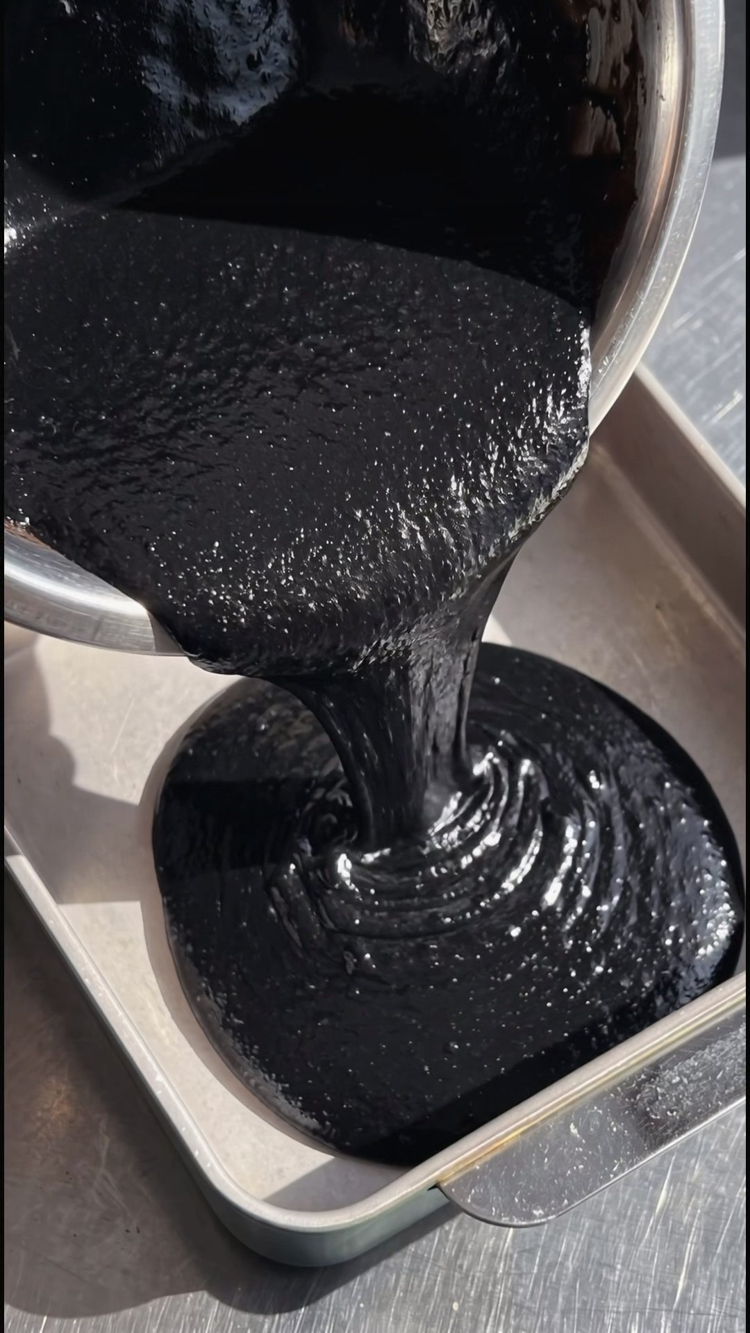 Glossy black velvet batter poured into a rectangular baking dish for a Halloween cake recipe by Ube Nolia