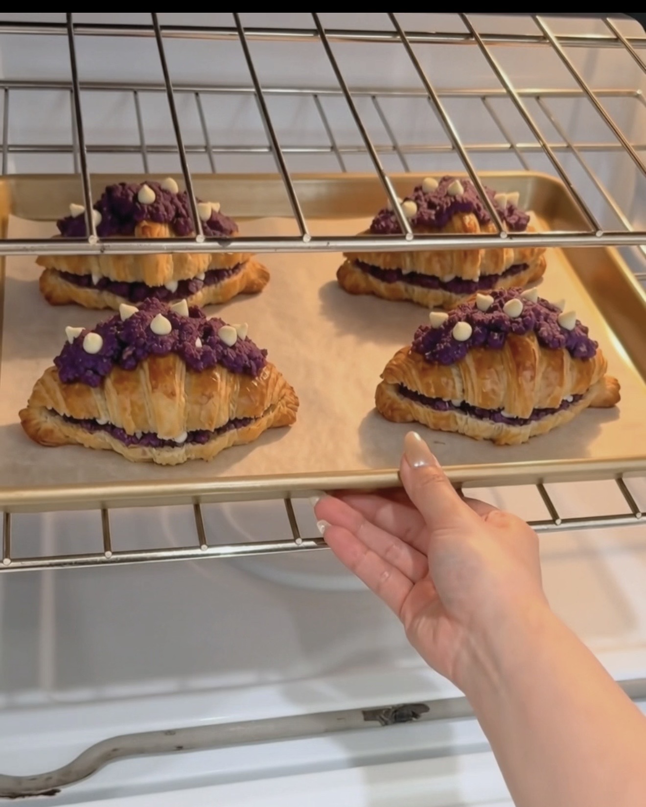 Tabuleiro de ube crookies UBE NOLIA® acabado de sair do forno com camadas de croissant douradas e cobertura de biscoito de ube roxo (inhame roxo) com pepitas de chocolate branco