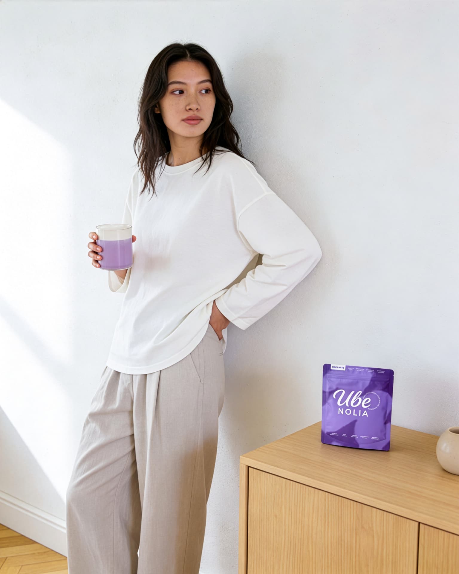 Woman holding a creamy ube latte with Ube Nolia powder pouch | Ube Nolia