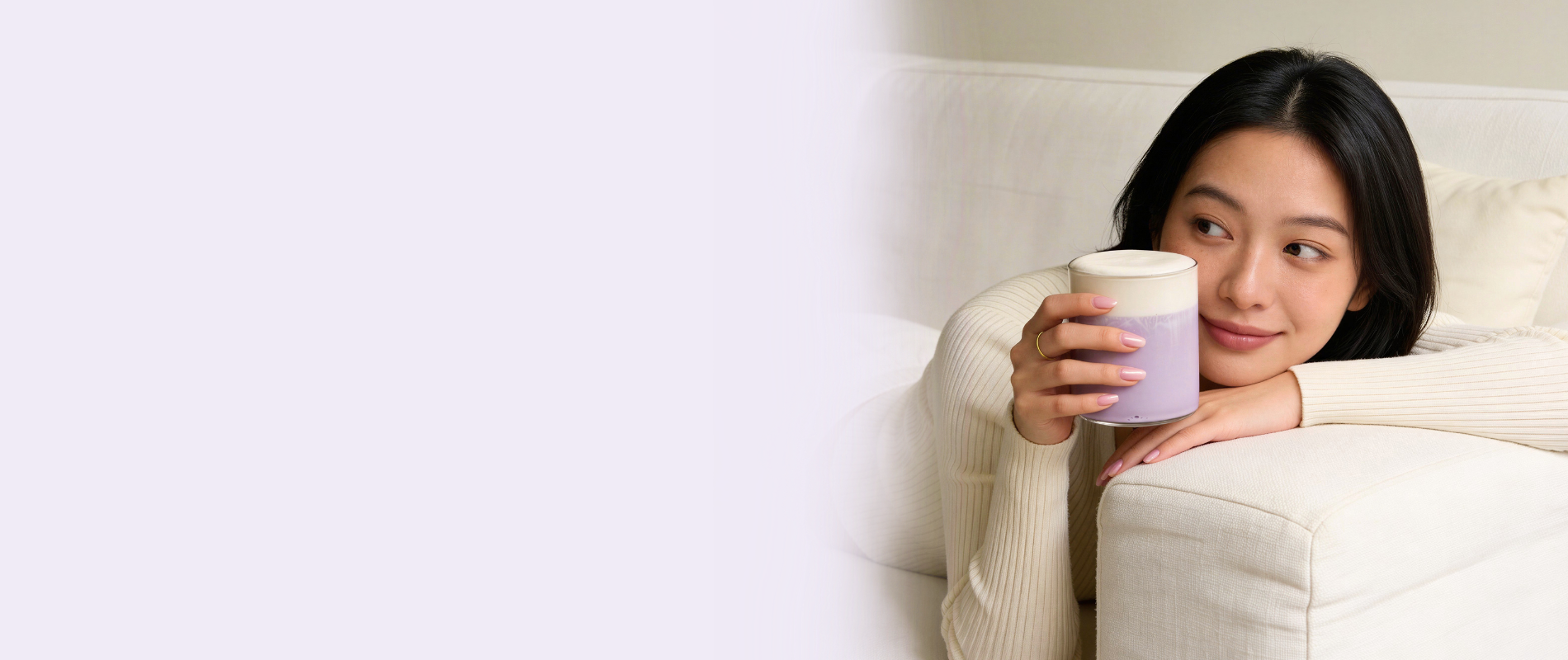 Woman relaxing on a sofa enjoying a creamy ube latte made with Ube Nolia ube powder