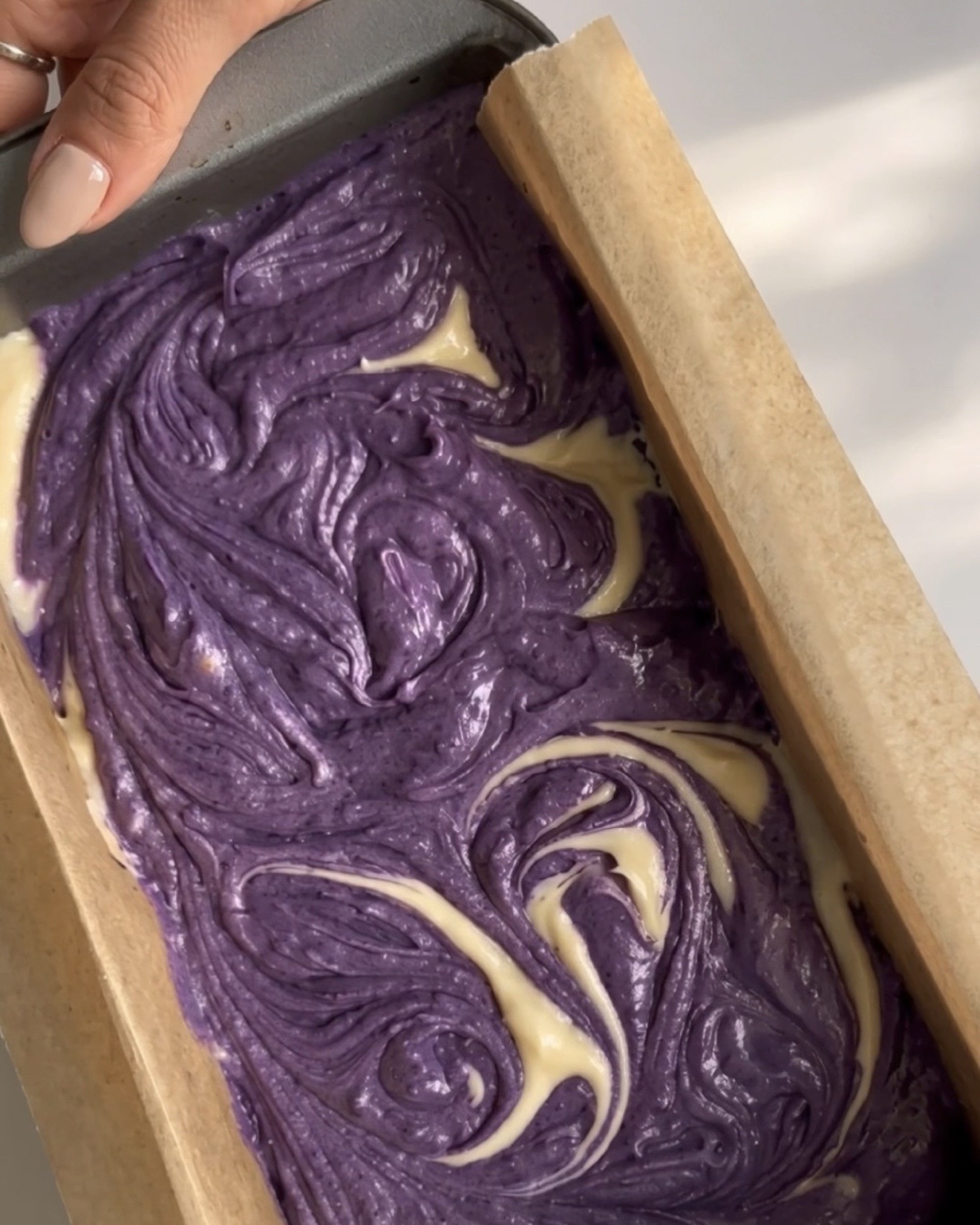 Purple and vanilla batters swirled together into a marble pattern in the loaf pan for Ube Nolia ube marble pound cake