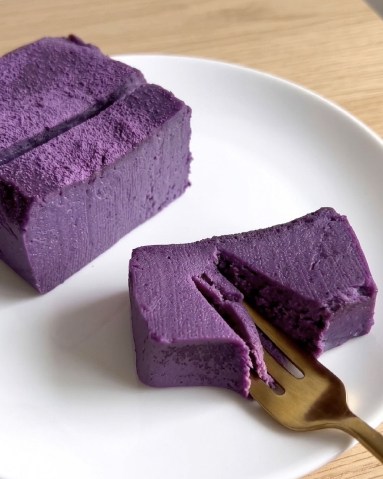 Brownies de fudge de tofu e ube Ube Nolia (fudge de inhame roxo filipino) prontos, fatiados em um prato branco com um garfo dourado