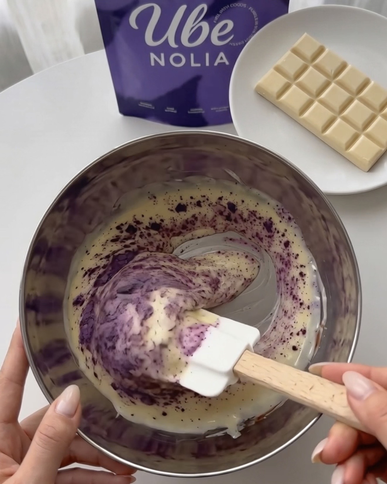 Whisking Ube Nolia ube powder into melted white chocolate for purple pistachio quinoa bites