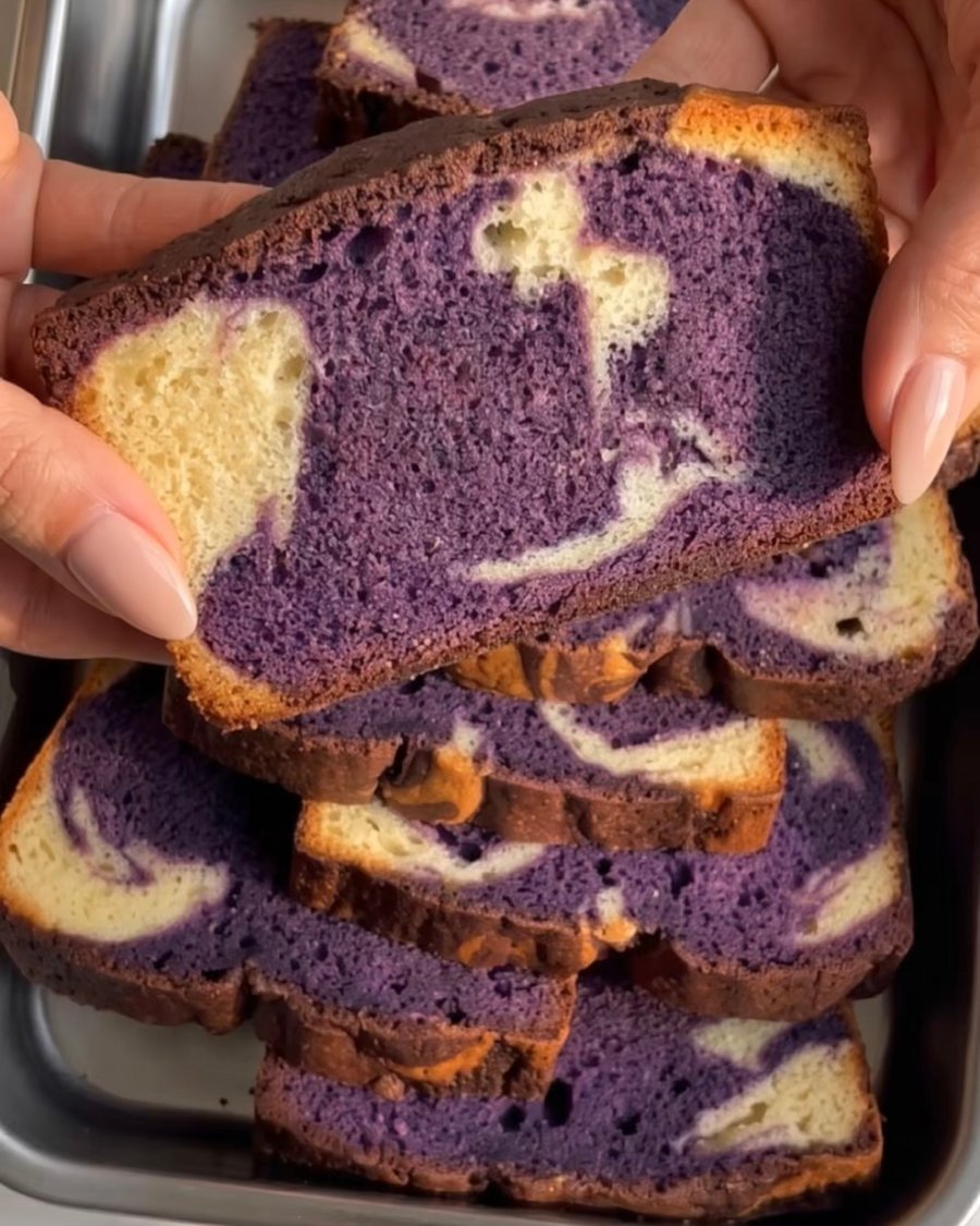 Hand holding a slice of ube marble pound cake with a purple and vanilla swirl, baked with Ube Nolia ube powder