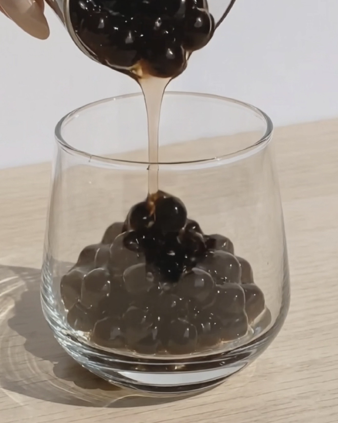 Dark brown sugar syrup for ube boba being spooned from a small jar by Ube Nolia