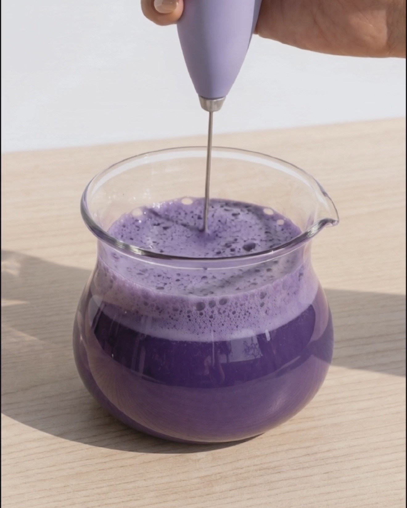 Real Ube Nolia purple yam powder being whisked into oat milk for a naturally purple ube bubble tea base