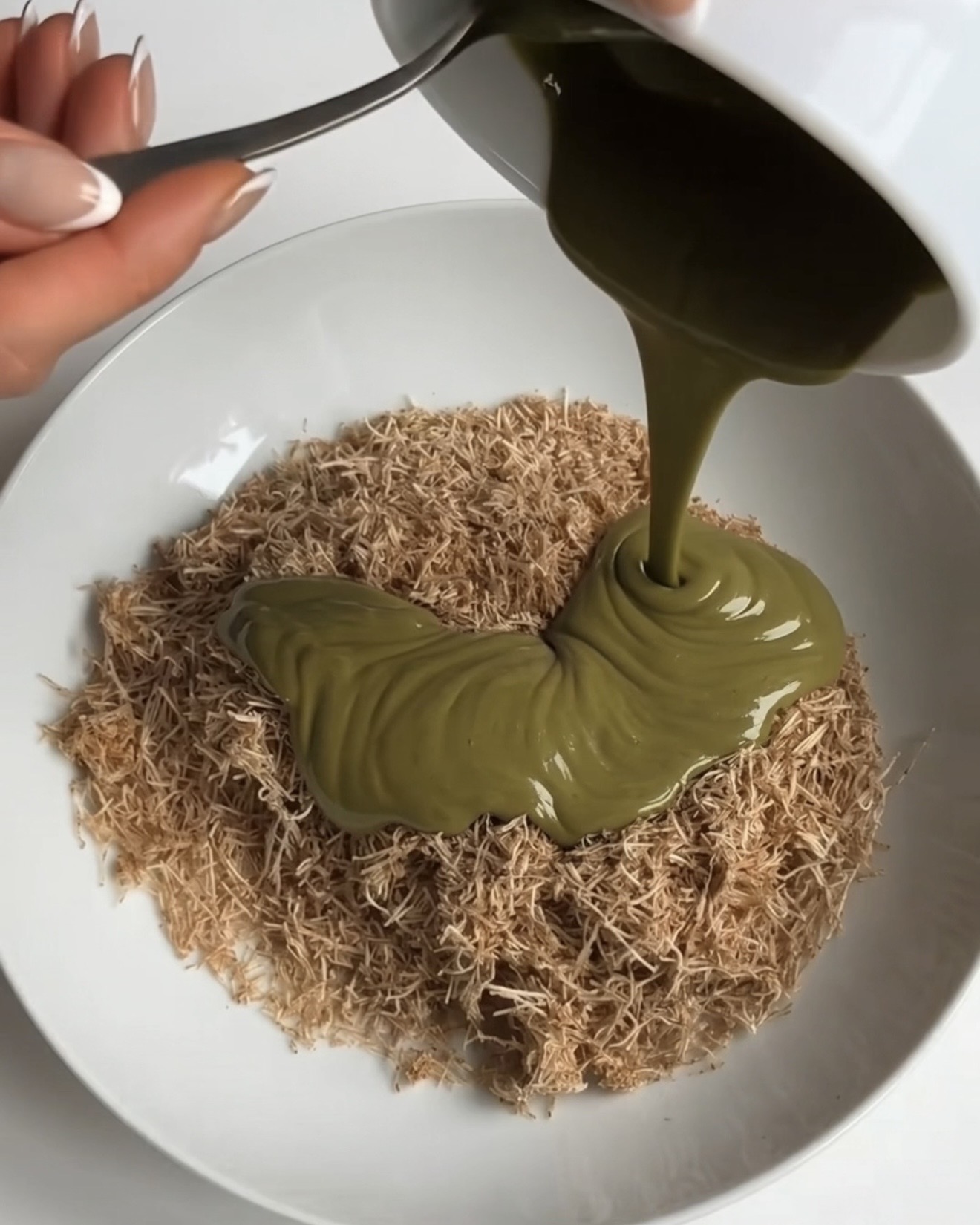 Pistachio cream poured over a bowl of toasted kataifi pastry for the Ube Dubai chocolate brownie bars filling by Ube Nolia