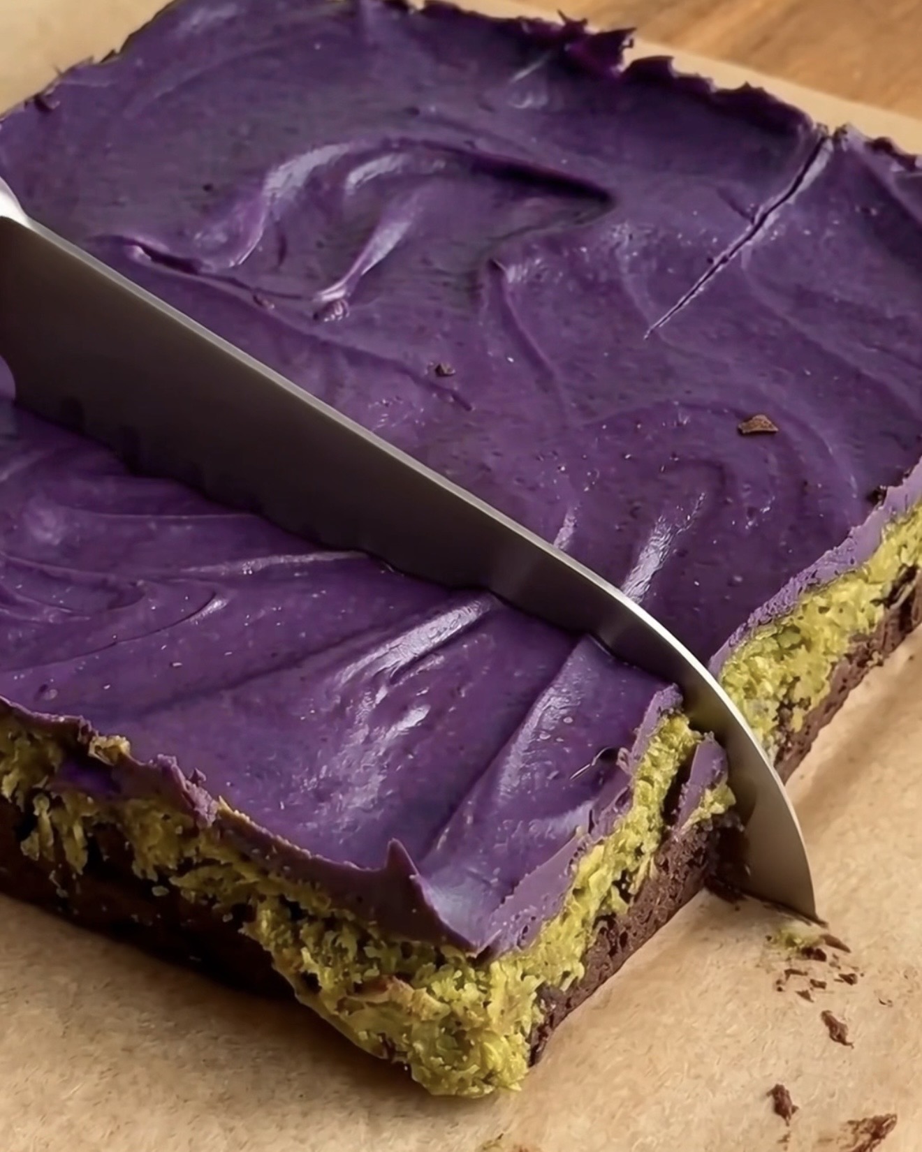Slicing chilled Ube Dubai chocolate brownie bars showing the brownie, pistachio kataifi and ube white chocolate layers by Ube Nolia