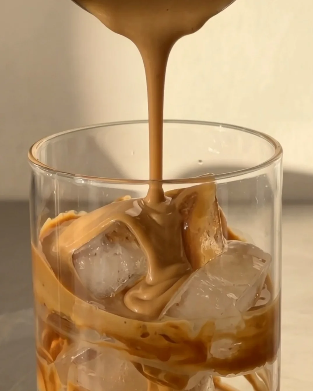 Biscoff cream poured over ice cubes in a glass swirled with Lotus Biscoff spread