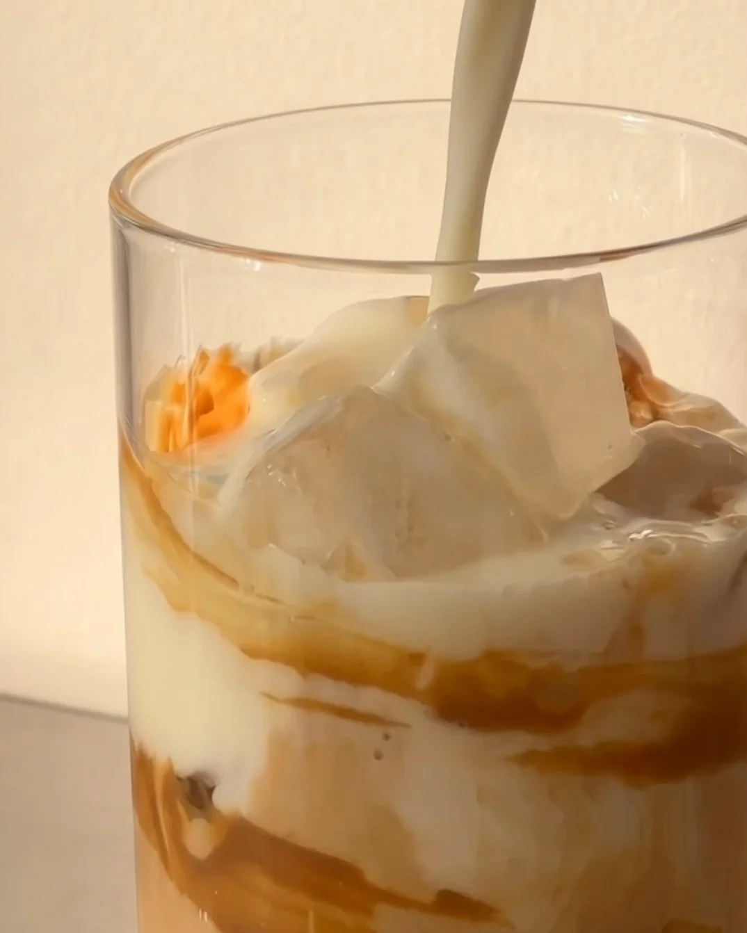 Oat milk poured over ice and Biscoff cream for an iced Biscoff ube latte