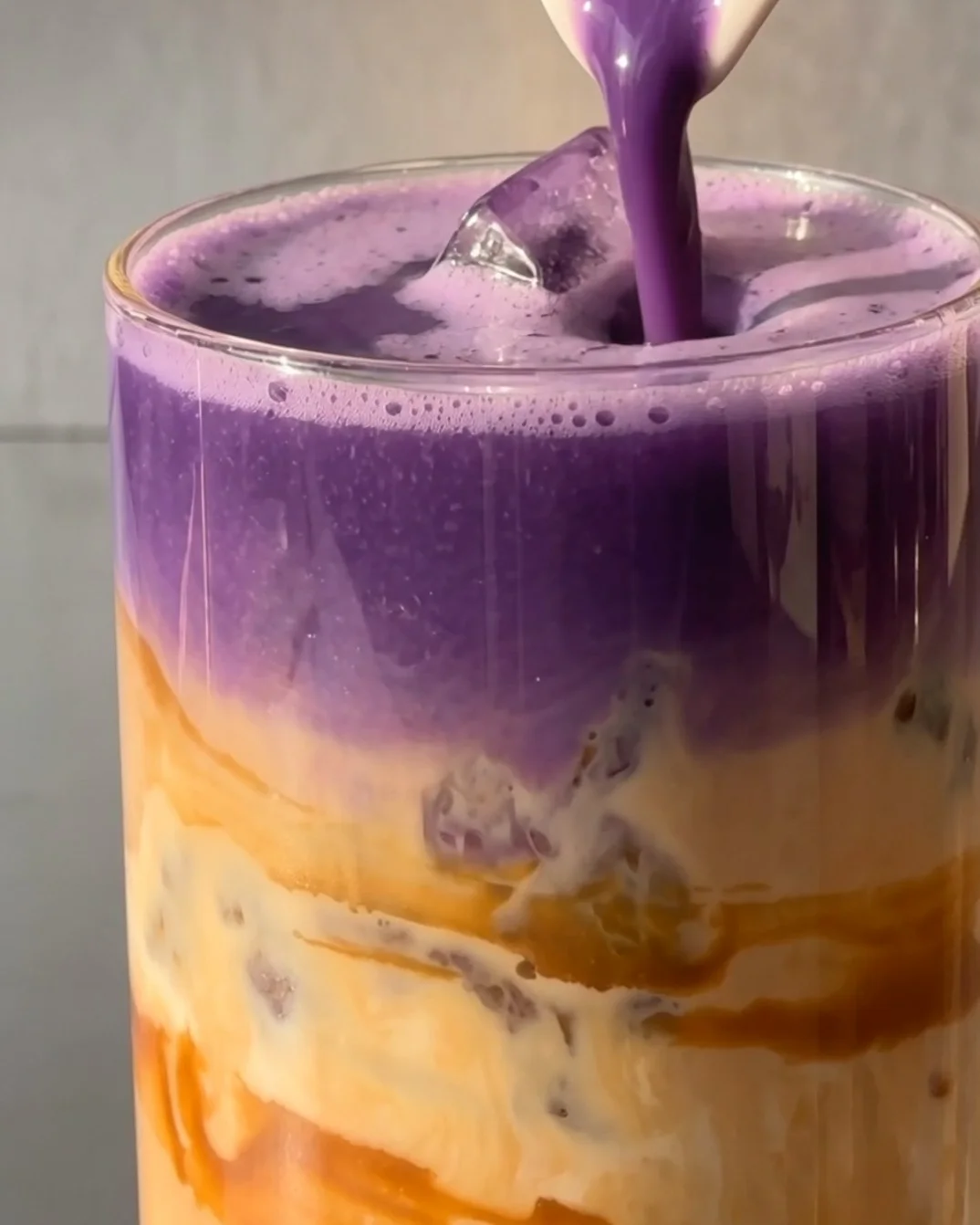 Purple ube mixture poured over the milk, creating the layered Biscoff ube latte