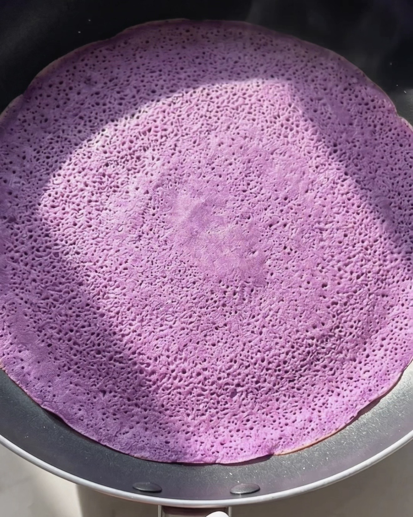 Steker tunn lila ube dadar gulung crêpe i en nonstick-panna