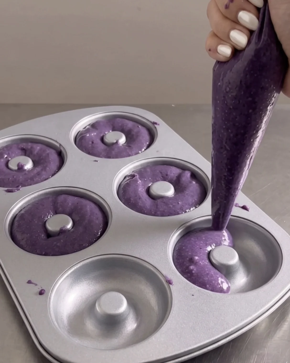 Piping purple ube batter into a donut pan | Ube Nolia