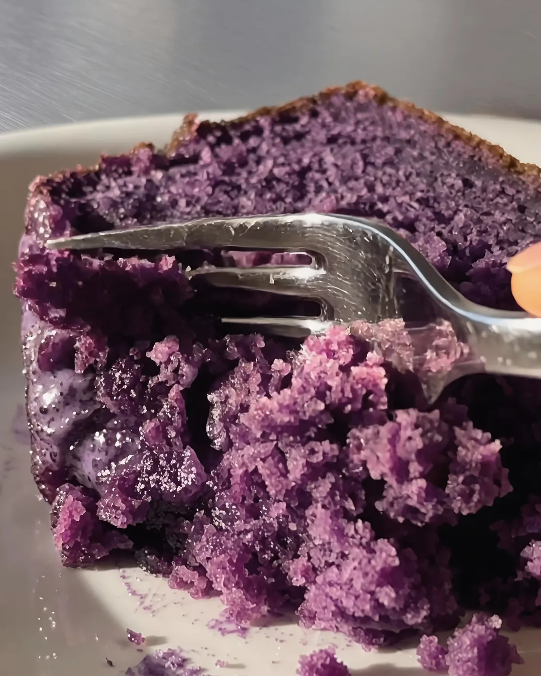 Fork cutting into a moist slice of ube banana bread | Ube Nolia