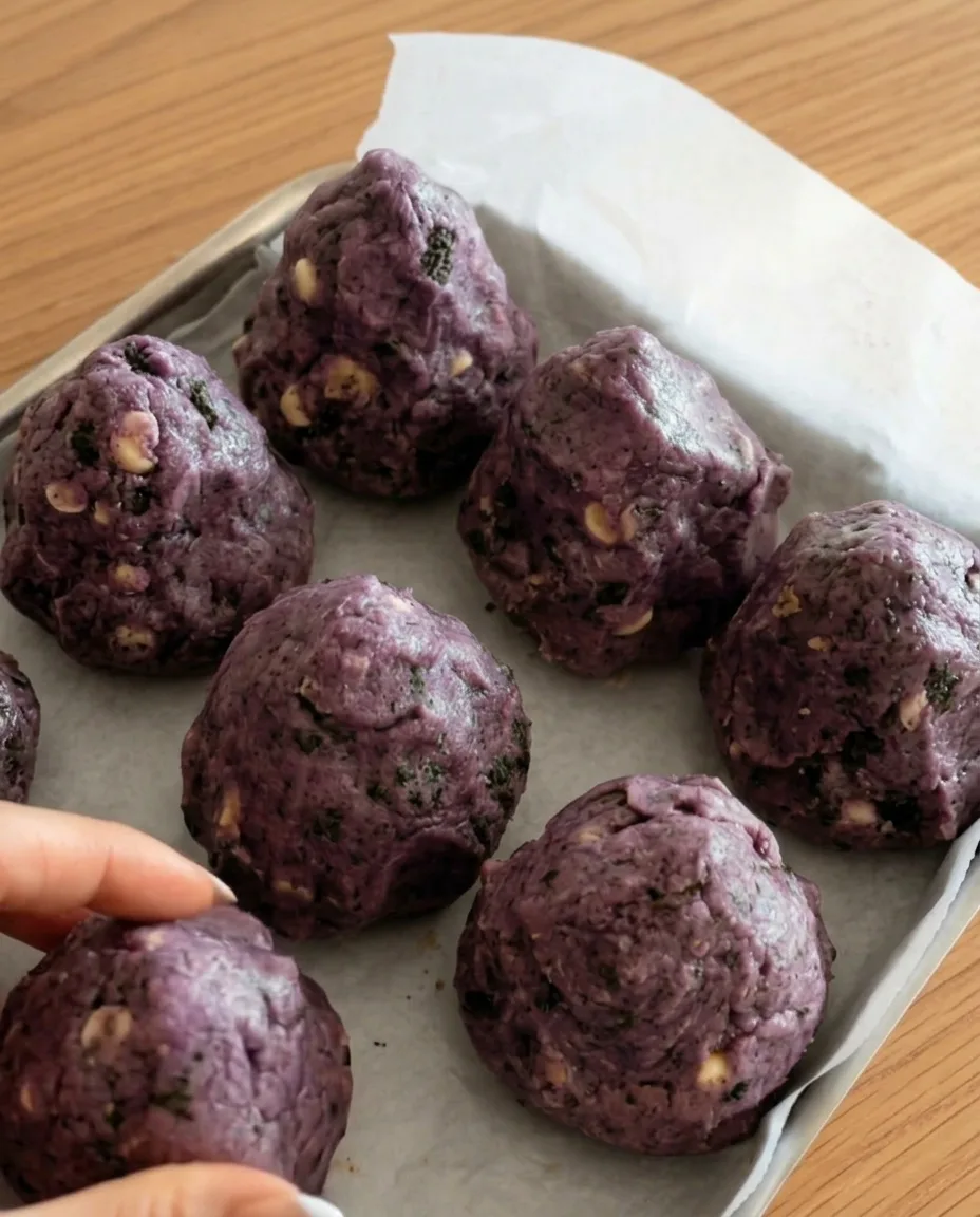 Paarse ube Oreo koekjesdeegballen op bakpapier klaar om in te vriezen voor New York style chunky koekjes