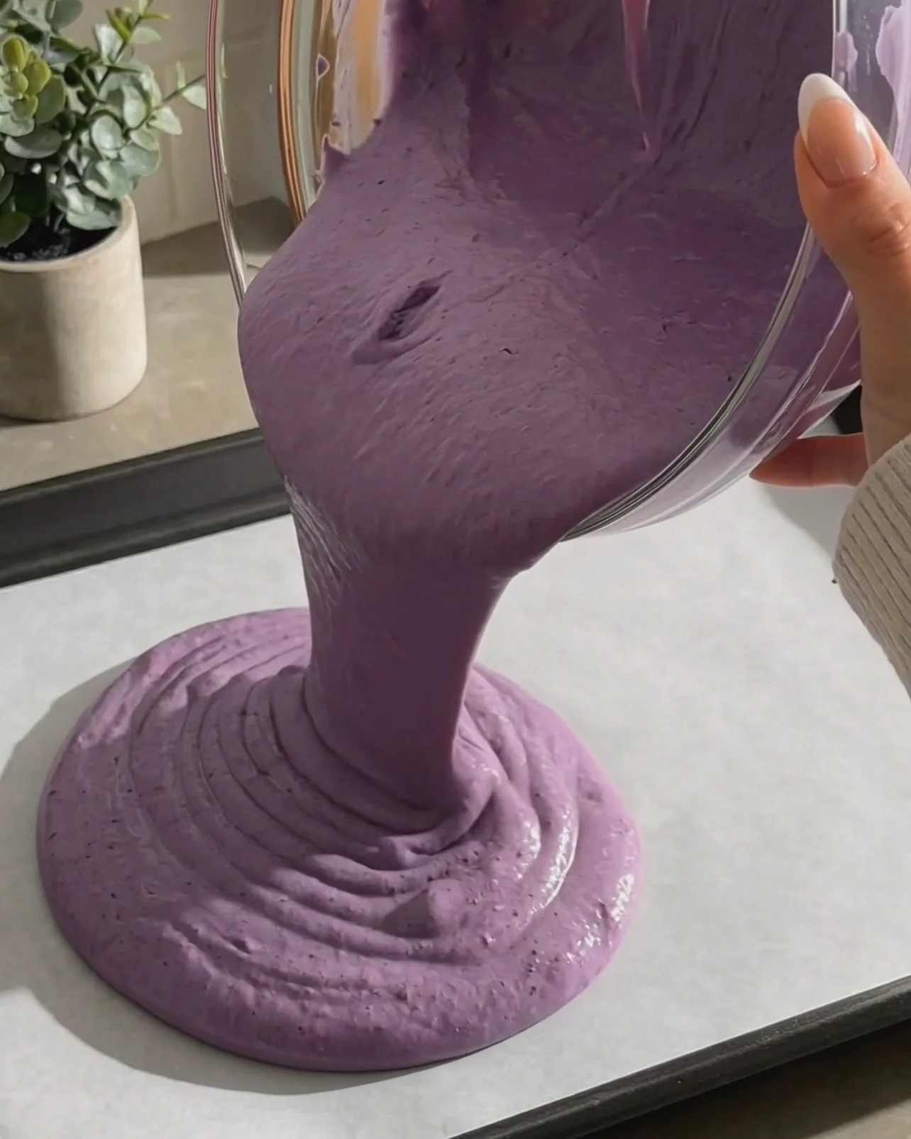 Pouring vibrant purple ube chiffon cake batter onto a parchment-lined baking sheet by Ube Nolia
