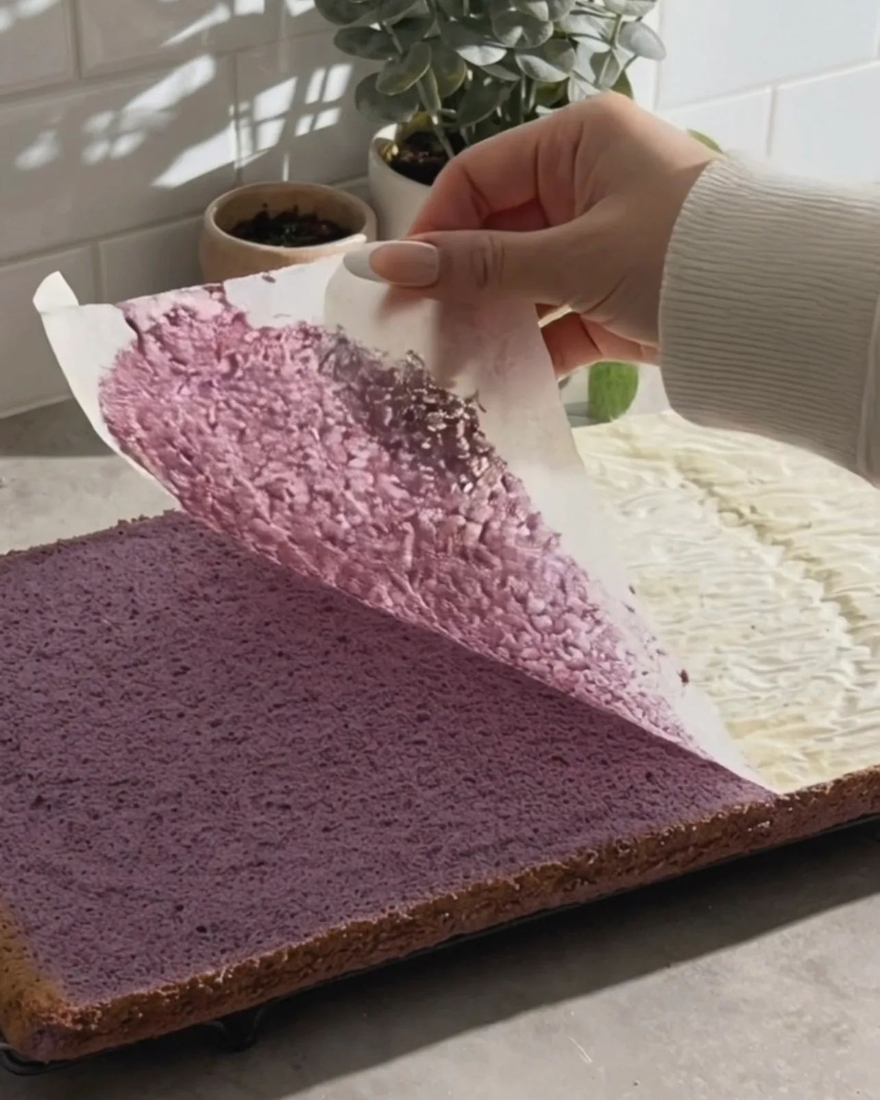 Peeling parchment paper off a freshly baked purple ube chiffon cake sheet by Ube Nolia