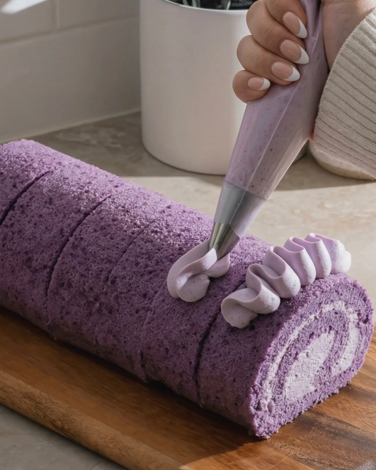 Piping decorative ube whipped cream rosettes on top of the finished purple ube roll cake by Ube Nolia